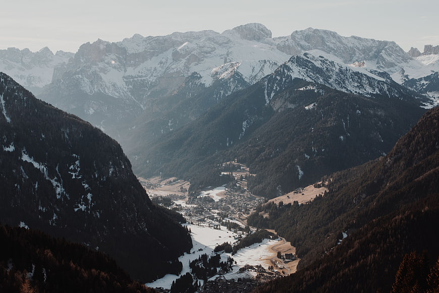 Snowy Alpine Valley with Mountain Village and Forested Slopes