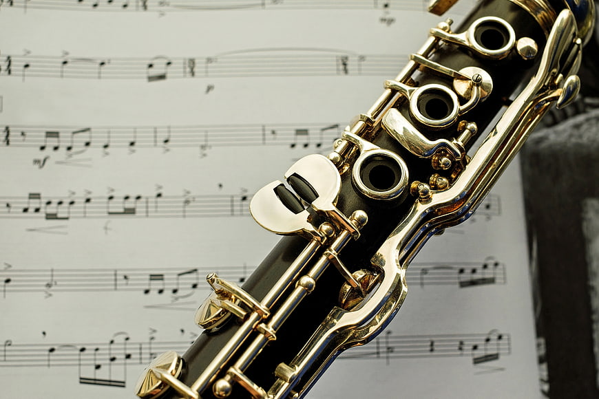 Close-up of a clarinet with silver keys resting on sheet music