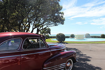 Vintage Red Classic Car Parked Near Ocean Fountain