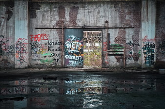 Abandoned warehouse interior with graffiti and puddle reflection