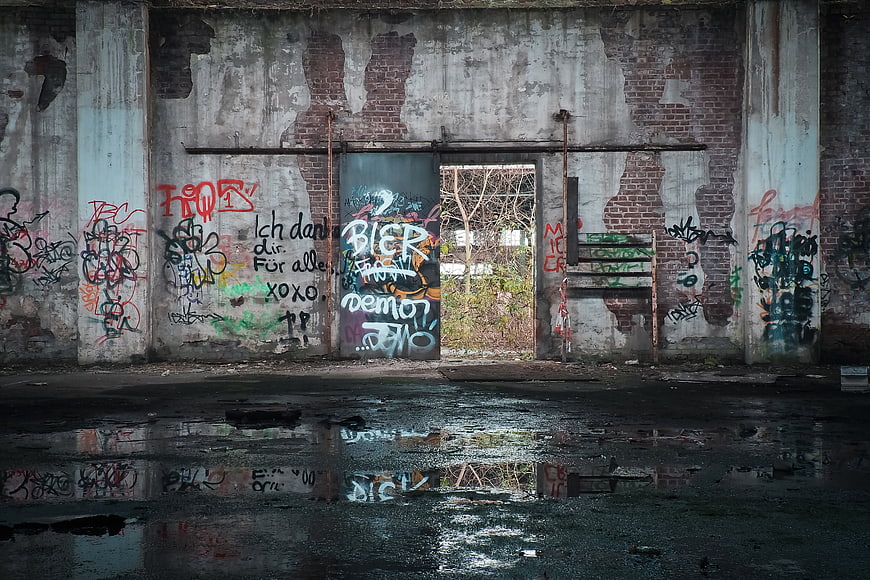 Abandoned warehouse interior with graffiti and puddle reflection