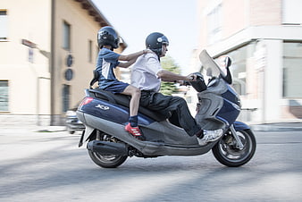 Father and son riding blue scooter in motion