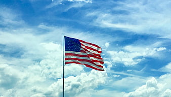 American Flag Waving Against Blue Sky with Clouds