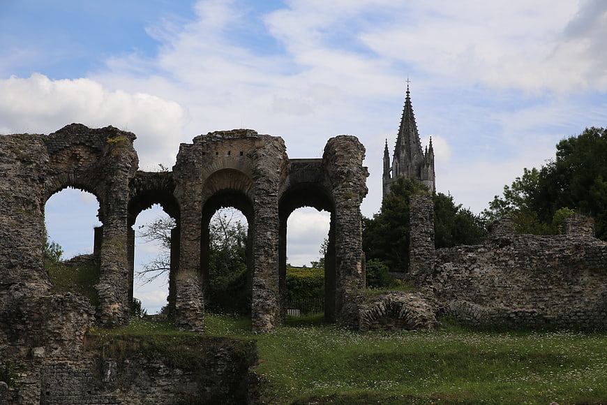 Ancient stone ruins with arches and distant church spire