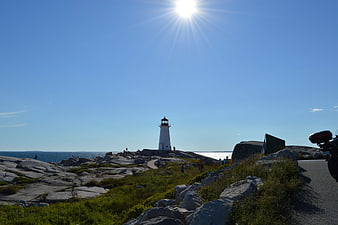 White Lighthouse on Rocky Coastline with Sunburst