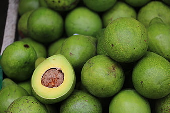 Fresh Green Avocados In Market Crate With One Cut Open