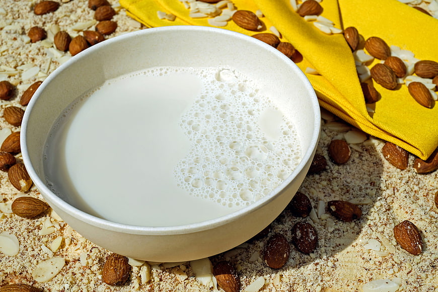 Bowl of almond milk surrounded by almonds and almond flour
