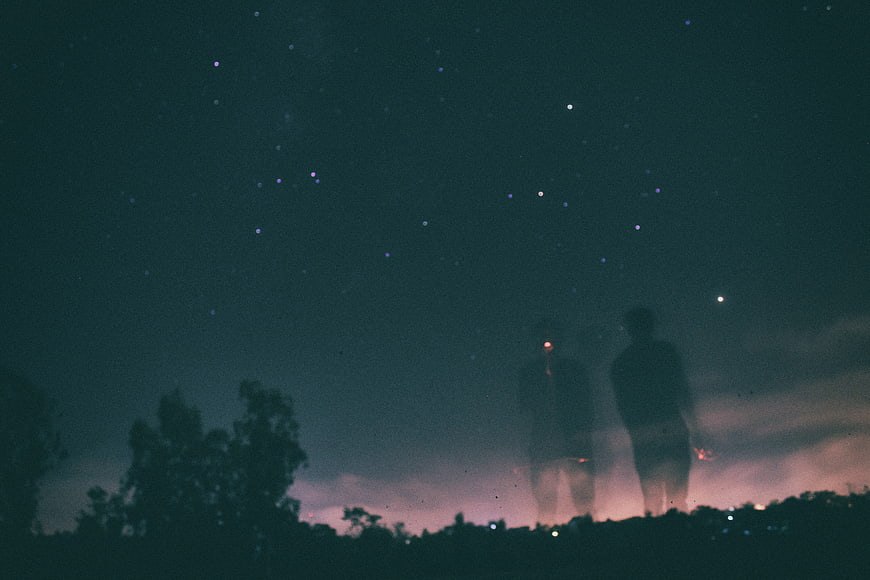 Silhouettes of Two People Under Starry Night Sky