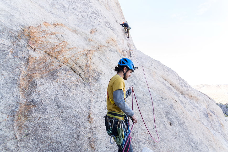Rock Climber Belaying Partner on Granite Cliff