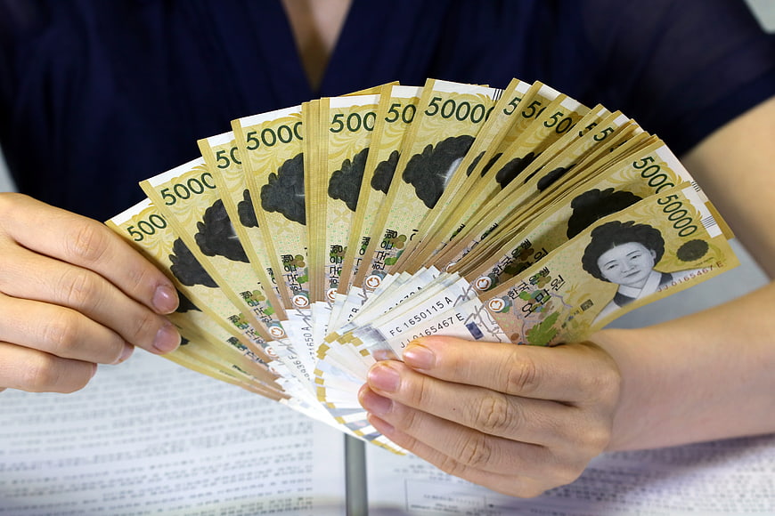 Hands holding fan of South Korean 5000 won banknotes