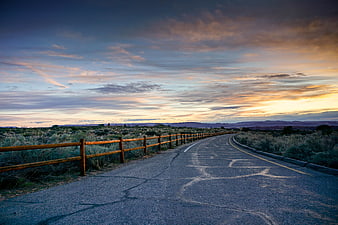 Winding Desert Road at Sunset with Wooden Fence