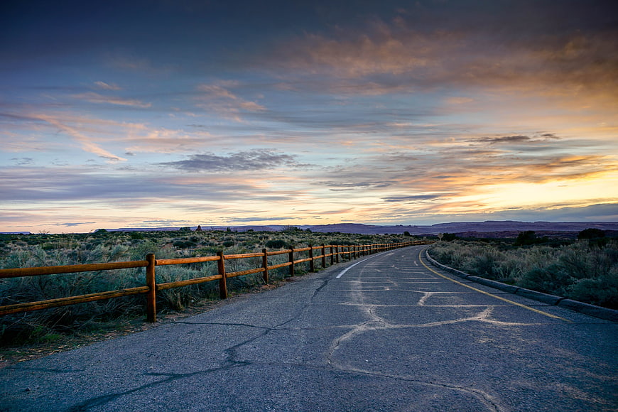 Winding Desert Road at Sunset with Wooden Fence