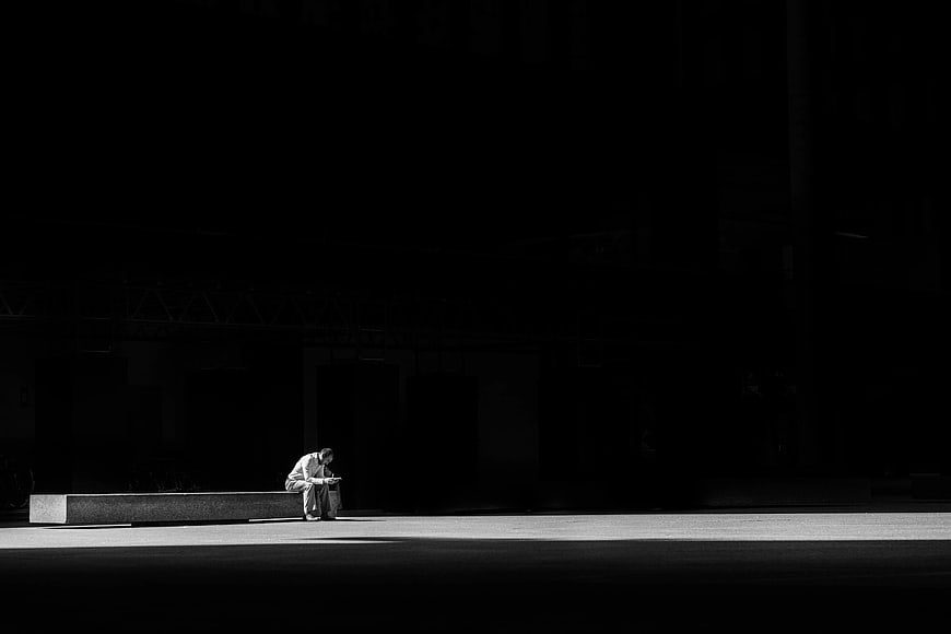 Lone Man Sitting on Bench in Dark Urban Space