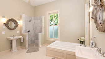 Elegant beige bathroom interior with marble shower and white soaking tub