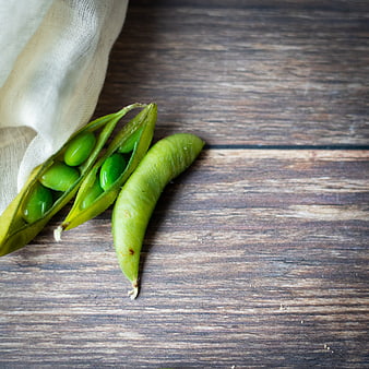 Fresh green peas spilling from linen bag on rustic wood