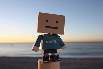 Small Me Paper Toy Figure on Beach at Sunset