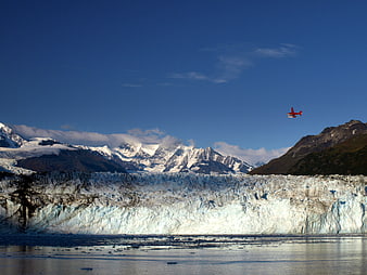 Red airplane flying over Patagonian glacier and mountains