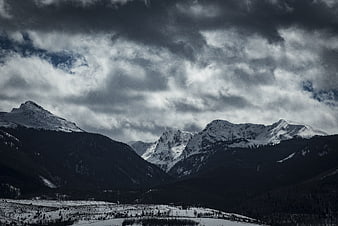 Dramatic Snow-Capped Mountain Range Under Stormy Clouds
