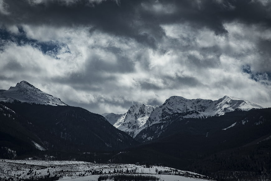 Dramatic Snow-Capped Mountain Range Under Stormy Clouds