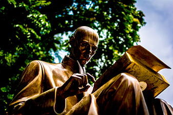 Low angle view of bronze statue reading book outdoors