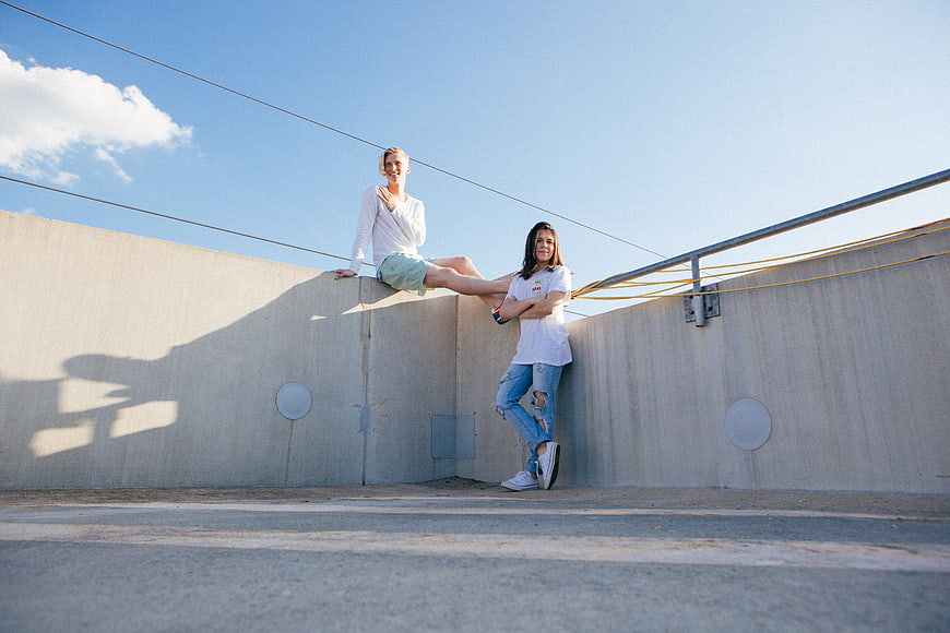 Two women relaxing on a concrete rooftop wall