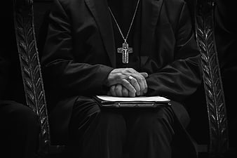 Black and white close-up of a Catholic priest's hands and cross
