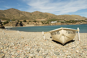 White fishing boat on pebble beach with mountains
