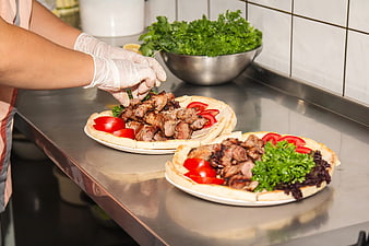 Chef preparing grilled meat platter with fresh vegetables in kitchen