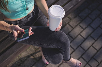Woman on bench with coffee and smartphone