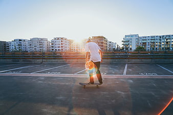 Man skateboarding on rooftop parking lot at sunset