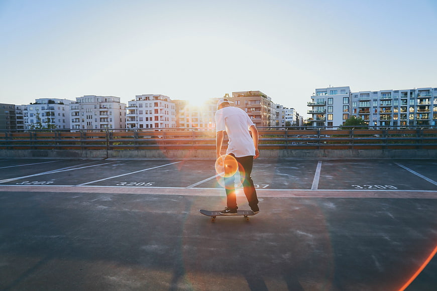 Man skateboarding on rooftop parking lot at sunset