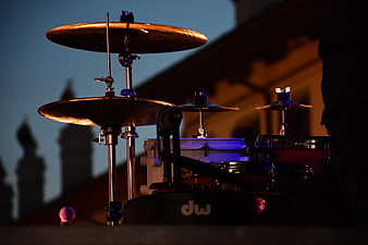 Drum kit cymbals on stage at dusk with city skyline