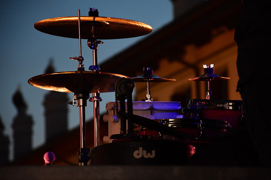 Drum kit cymbals on stage at dusk with city skyline
