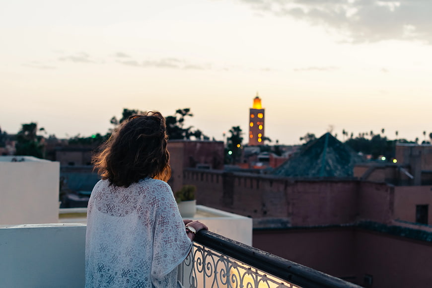 Woman on Rooftop Balcony Looking at Cityscape at Sunset