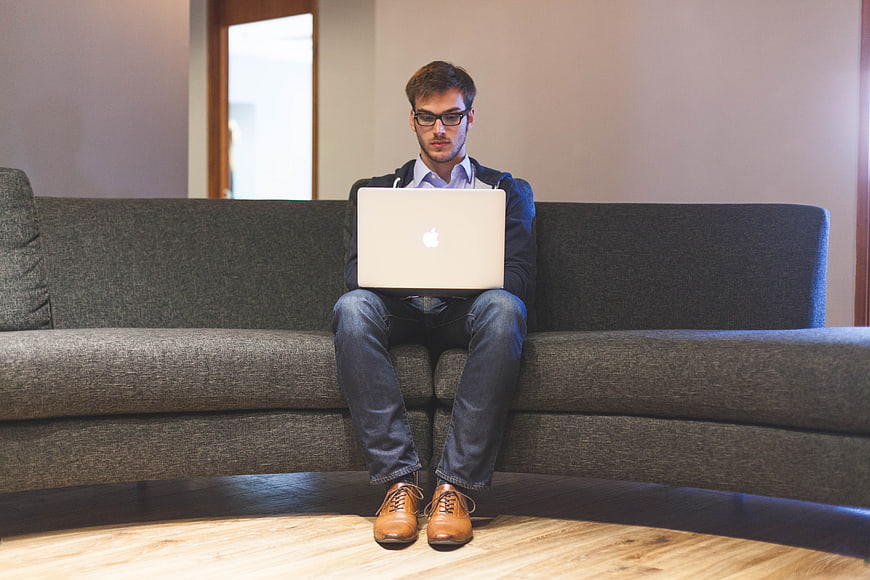 Young businessman working on laptop while sitting on couch