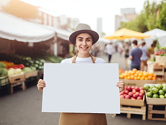 Happy woman holding blank sign at farmers market
