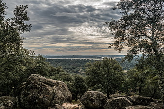 Dramatic cloudy sky over rocky forest landscape with distant river