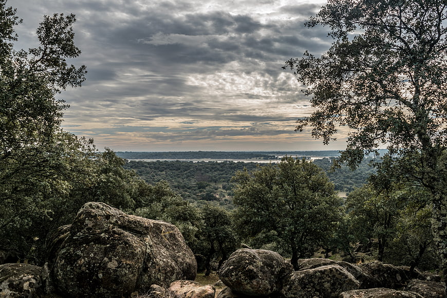 Dramatic cloudy sky over rocky forest landscape with distant river