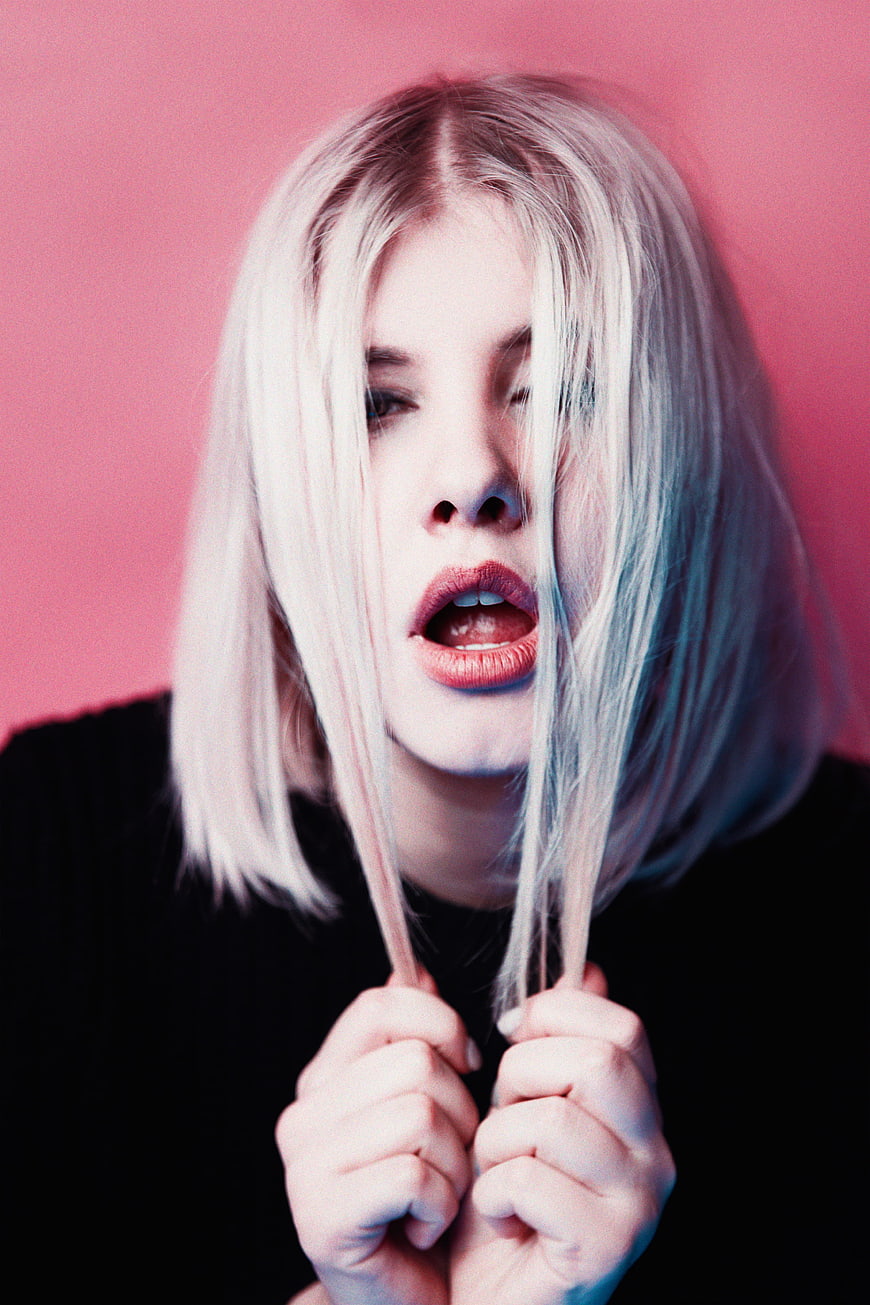 Edgy blonde woman portrait with pink background and blue lighting