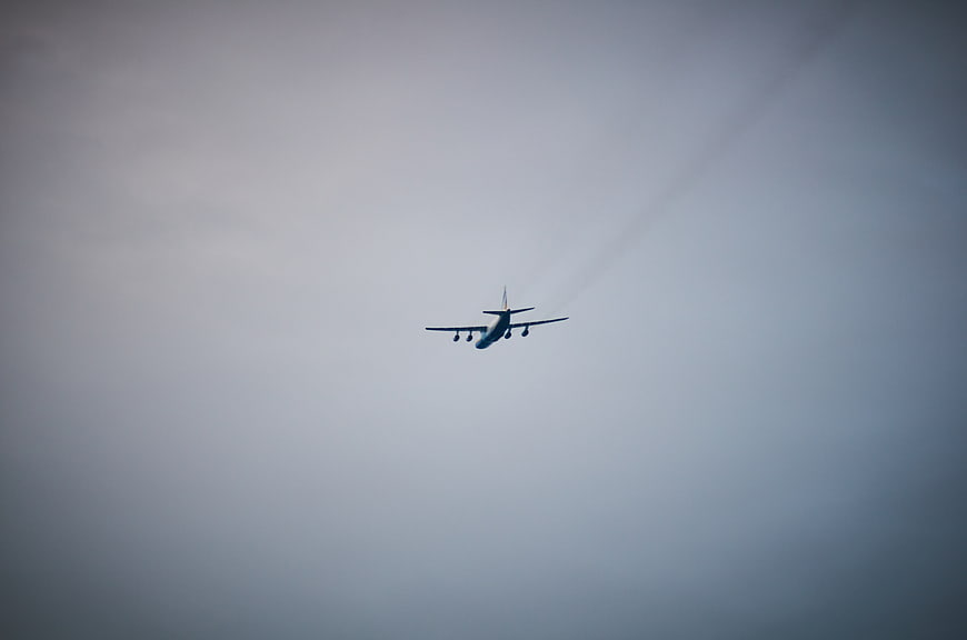 Airplane Flying in Overcast Sky with Contrails