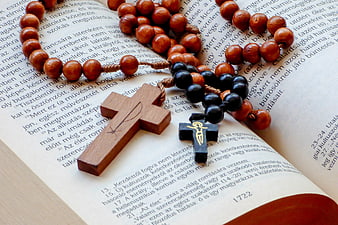 Wooden Crosses and Rosary Beads on Open Bible Pages