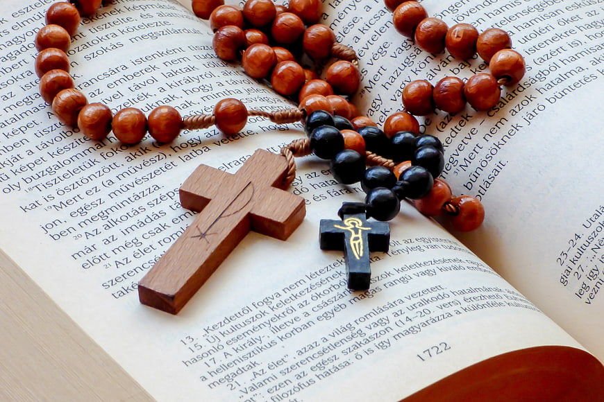 Wooden Crosses and Rosary Beads on Open Bible Pages