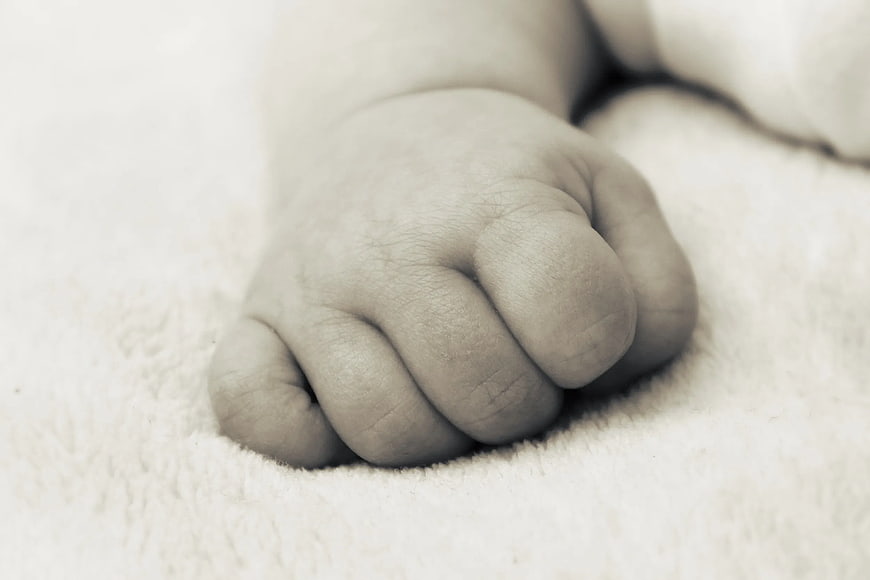 Close-up of newborn baby's tiny fist on soft blanket