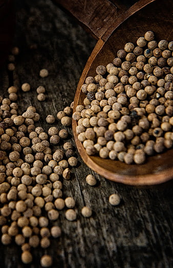 White peppercorns in wooden spoon on rustic table