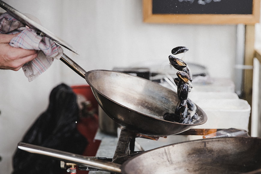 Chef tossing mussels in a wok