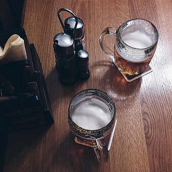 Two mugs of beer on a wooden pub table