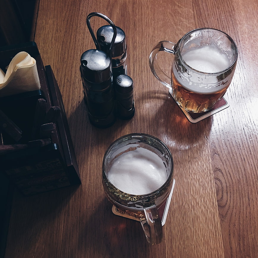 Two mugs of beer on a wooden pub table