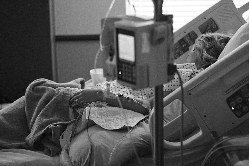 Black and white photo of a woman in a hospital bed with medical equipment
