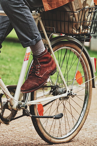 Close-up of man's brown boots on vintage bicycle pedal