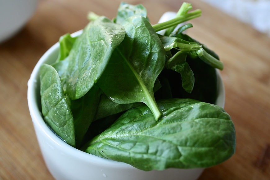 Fresh Raw Spinach Leaves in White Bowl on Wooden Table